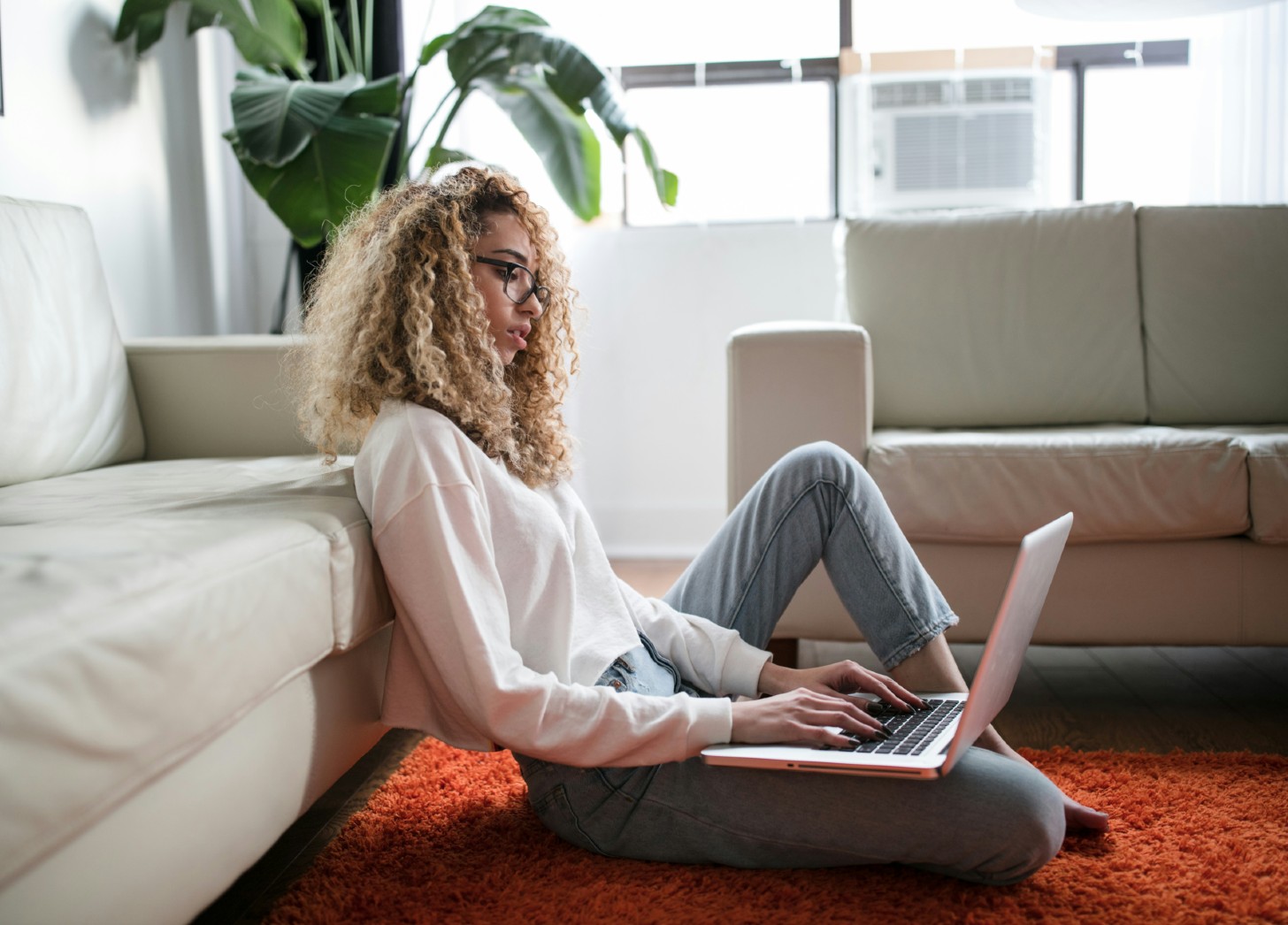 Woman sitting on a couch with a laptop doing the first edit on her memoir manuscript