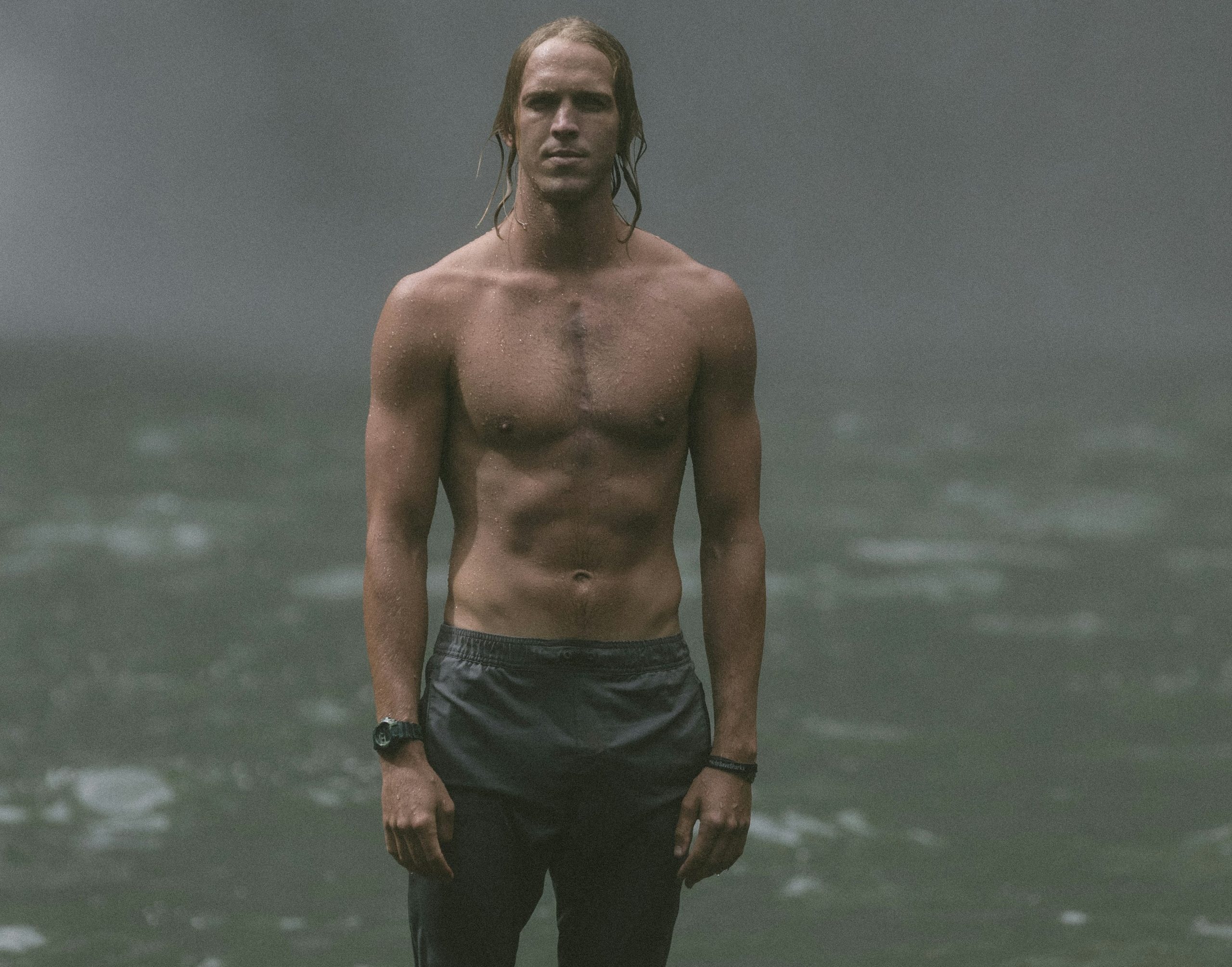 Shirtless man standing by water